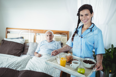 Nurse serving breakfast to senior man