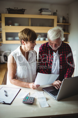 Senior couple paying bills online on laptop