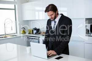 Businessman using laptop in kitchen