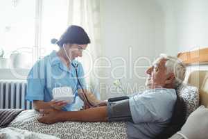 Nurse checking blood pressure of senior man