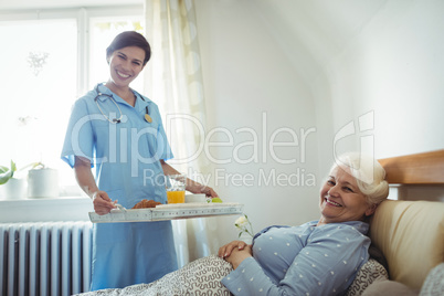 Nurse serving breakfast to senior woman