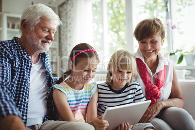 Grandchildren using digital tablet with their grandparents