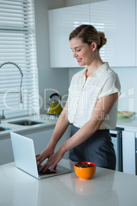 Woman using laptop in kitchen