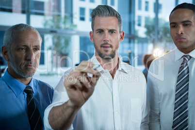 Businessman writing with marker on glass