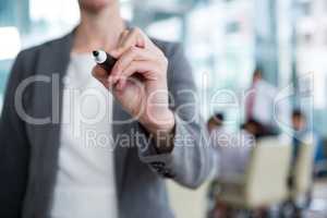 Businesswoman writing with marker on glass