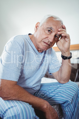 Frustrated senior man sitting on bed