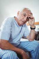 Frustrated senior man sitting on bed