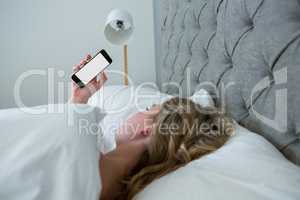 Young woman looking at mobile phone while sleeping