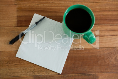 Close-up of coffee mug with blank paper and pen