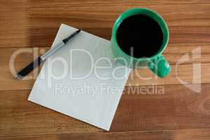 Close-up of coffee mug with blank paper and pen