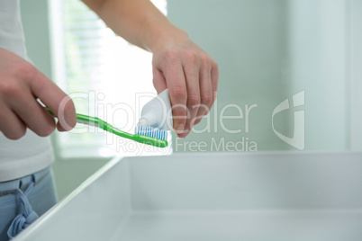 Woman putting toothpaste on brush in bathroom