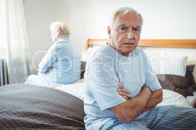 Sad senior couple sitting on bed