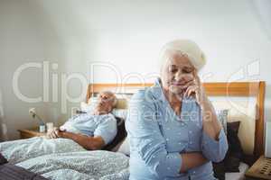 Worried senior woman sitting on bed