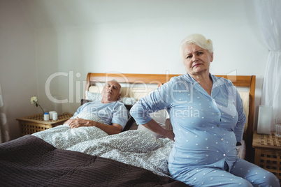 Senior woman suffering from backache sitting on bed