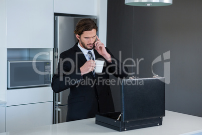 Businessman talking on mobile phone in kitchen