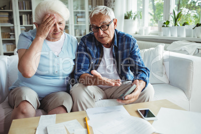 Worried senior couple interacting while checking the bills