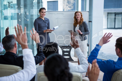 Colleagues raising their hands during meeting