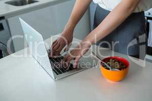 Woman using laptop in kitchen