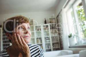 Thoughtful senior woman sitting on sofa in living room