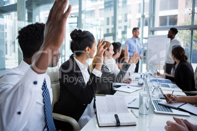 Colleagues raising their hands during meeting