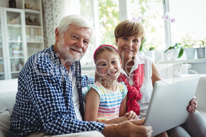 Grandparents and granddaughter using laptop in living room