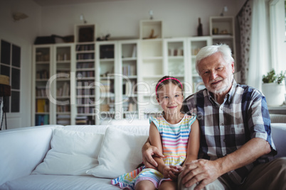 Portrait of senior man sitting with his granddaughter