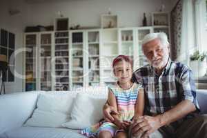 Portrait of senior man sitting with his granddaughter