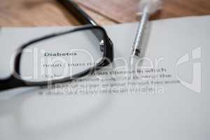 Close-up of injection with diabetes test paper and spectacle