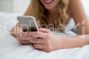 Woman lying on bed and using mobile phone on bed