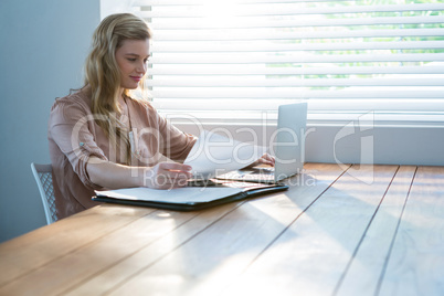 Woman looking at bill while using laptop