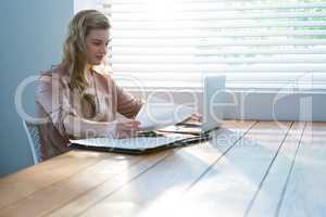 Woman looking at bill while using laptop