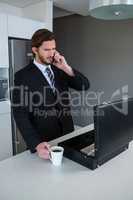 Businessman talking on mobile phone in kitchen