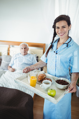 Nurse serving breakfast to senior man