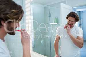 Man looking in mirror while brushing her teeth in bathroom