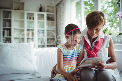 Senior woman and her granddaughter looking at a photo album