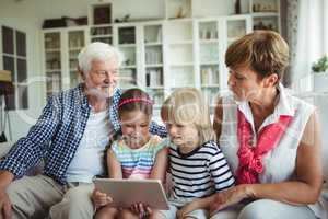 Grandchildren using digital tablet with their grandparents