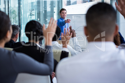 Colleagues raising their hands during meeting