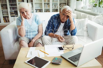 Worried senior couple sitting on sofa