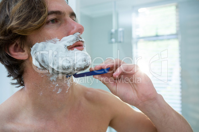 Man using a razor to shave his beard off