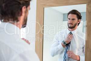 Man getting dressed in bedroom while looking at mirror
