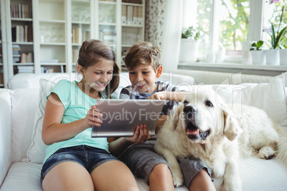 Children using digital tablet while sitting on a sofa