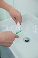 Woman putting toothpaste on brush in bathroom