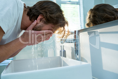 Man washing his face with water in bathroom