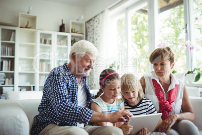 Grandchildren using digital tablet with their grandparents