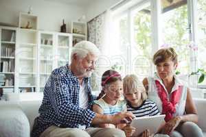 Grandchildren using digital tablet with their grandparents