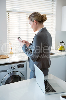 Woman using mobile phone in kitchen