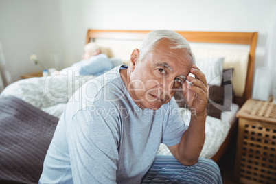 Frustrated senior man sitting on bed