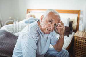 Frustrated senior man sitting on bed