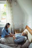 Nurse interacting with senior woman on bed