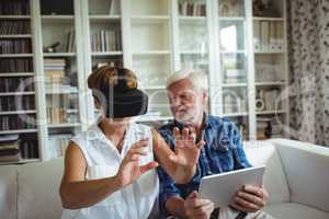 Senior couple using digital tablet and virtual reality headset